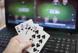 Dator med casinospel plus hand som håller spelkort